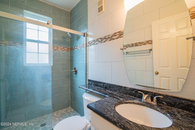 bathroom featuring tile walls, toilet, vanity, and an enclosed shower