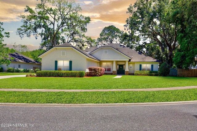 view of front facade featuring stucco siding, fence, and a yard