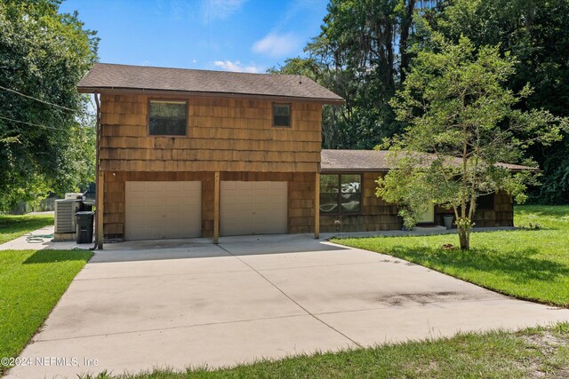 view of front facade featuring a garage, central AC unit, and a front yard