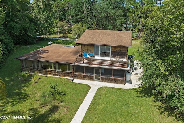 rear view of property featuring a sunroom and a lawn