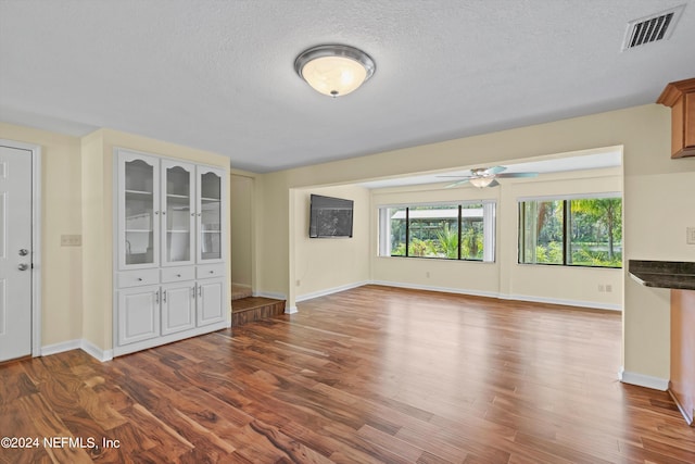 unfurnished living room with ceiling fan, a textured ceiling, and hardwood / wood-style flooring