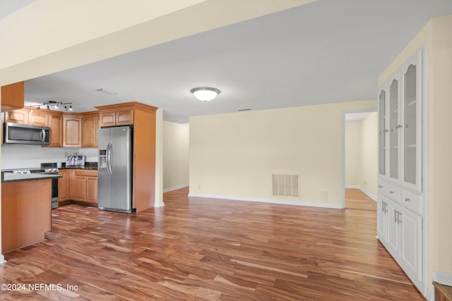 kitchen featuring appliances with stainless steel finishes, rail lighting, and hardwood / wood-style floors