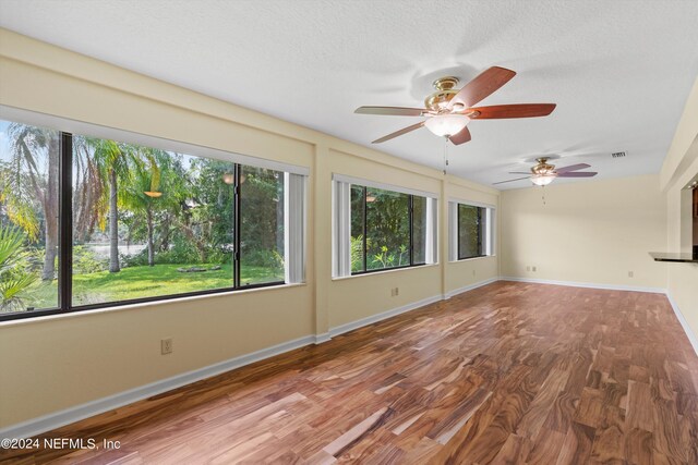 empty room featuring a textured ceiling, ceiling fan, and wood-type flooring