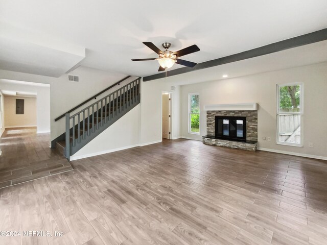 unfurnished living room featuring ceiling fan, a fireplace, light hardwood / wood-style floors, and electric panel