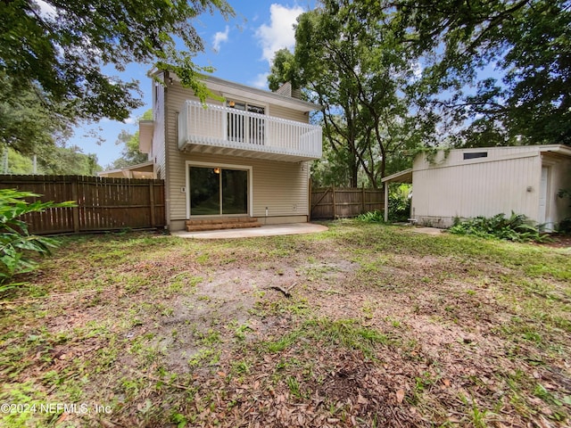 back of property featuring a lawn, a patio, and a balcony