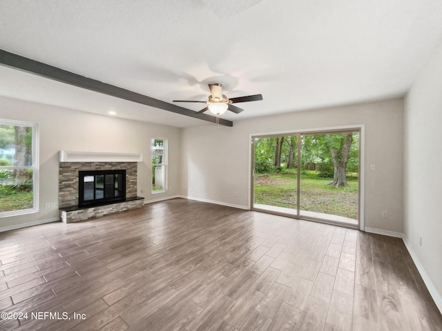 unfurnished living room with a stone fireplace and ceiling fan