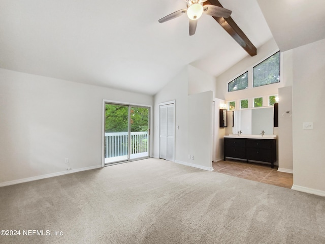 unfurnished living room with ceiling fan, light colored carpet, beam ceiling, and high vaulted ceiling