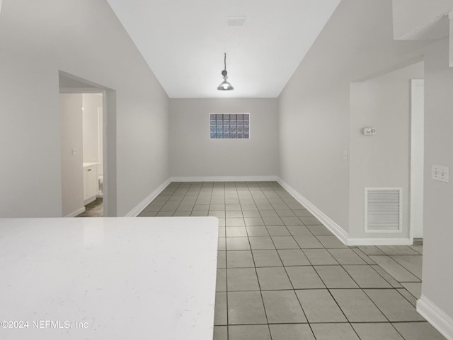 unfurnished dining area with light tile patterned floors and vaulted ceiling