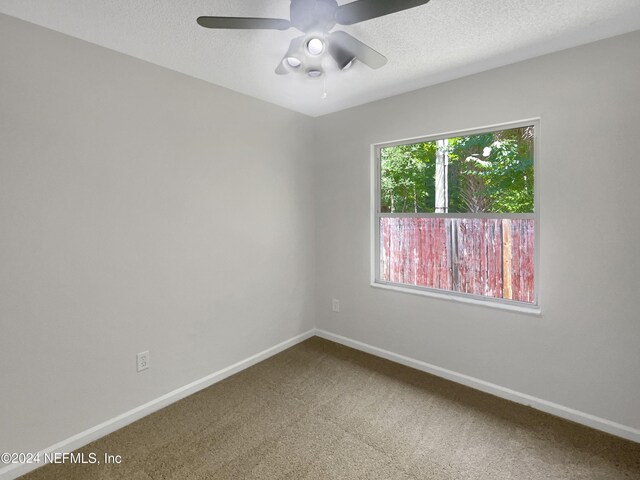 carpeted spare room with a textured ceiling and ceiling fan