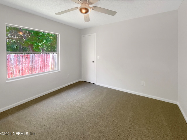 carpeted spare room featuring a textured ceiling and ceiling fan