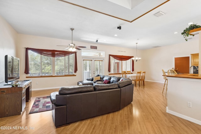 living room featuring sink, light hardwood / wood-style floors, ceiling fan with notable chandelier, and french doors