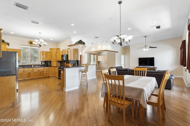 dining area featuring ceiling fan with notable chandelier, sink, and light hardwood / wood-style flooring