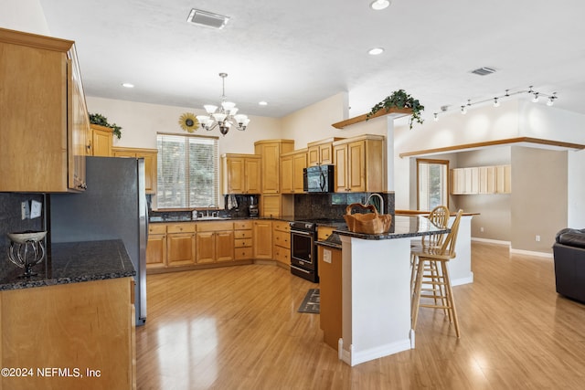 kitchen featuring light hardwood / wood-style floors, a breakfast bar, decorative backsplash, and black appliances