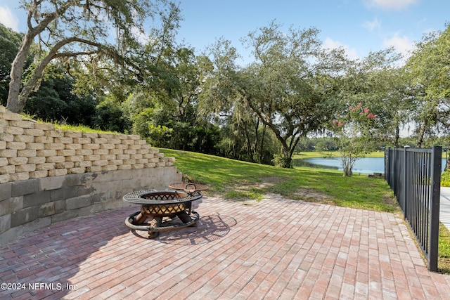 wooden terrace featuring a patio, an outdoor fire pit, a yard, and a water view