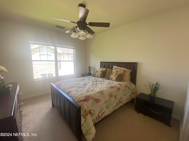 bedroom featuring a textured ceiling, light carpet, and ceiling fan