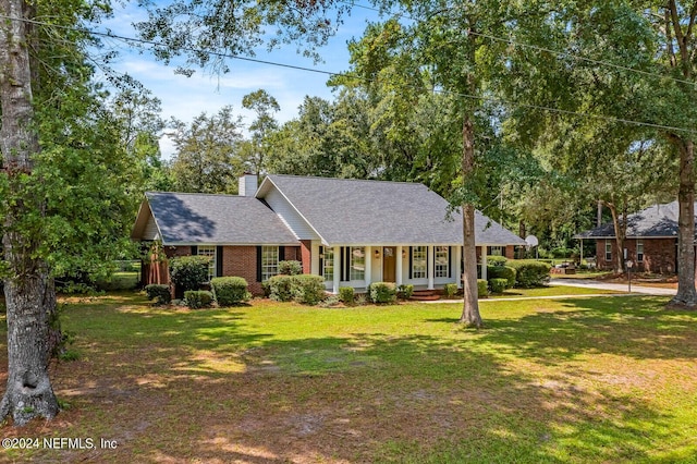 ranch-style home featuring covered porch and a front lawn