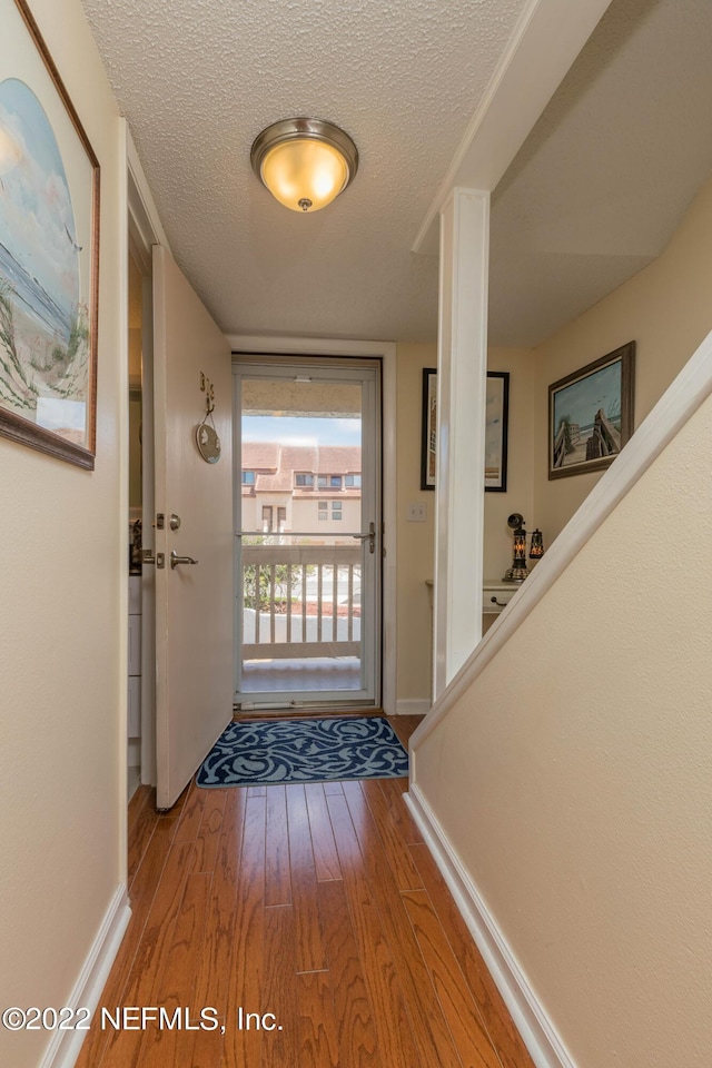 doorway to outside featuring wood-type flooring and a textured ceiling