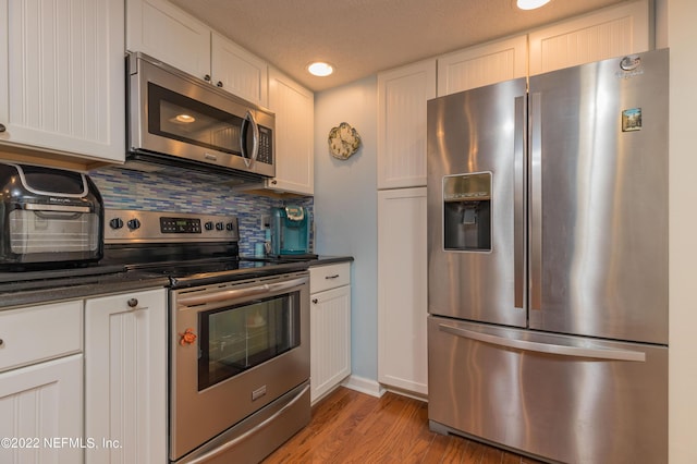 kitchen with white cabinetry, stainless steel appliances, decorative backsplash, and light hardwood / wood-style flooring