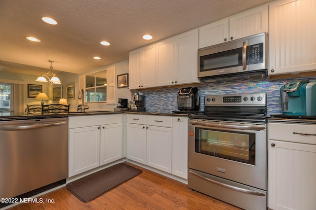 kitchen with white cabinetry, backsplash, stainless steel appliances, and sink