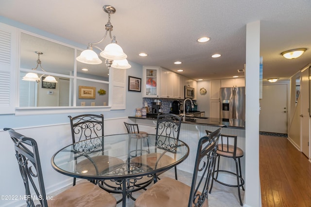 dining space featuring sink, a textured ceiling, and light hardwood / wood-style floors