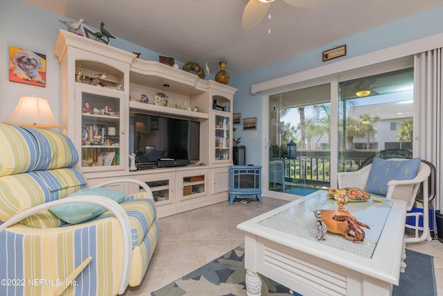 living room featuring ceiling fan, light tile patterned floors, and a textured ceiling