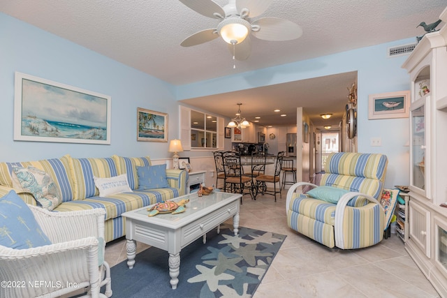 tiled living room with ceiling fan with notable chandelier and a textured ceiling