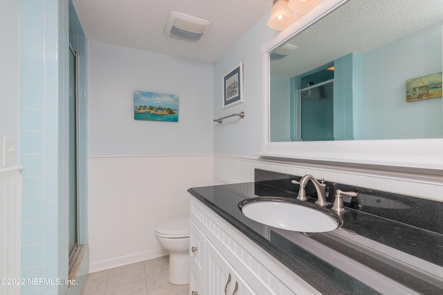 bathroom featuring tile patterned flooring, vanity, an enclosed shower, toilet, and a textured ceiling