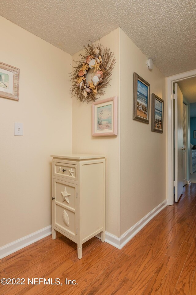 hallway featuring hardwood / wood-style floors and a textured ceiling