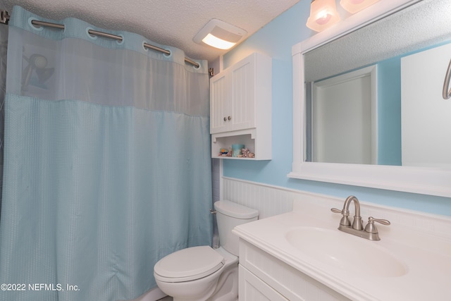 bathroom with wooden walls, vanity, toilet, a textured ceiling, and a shower with shower curtain