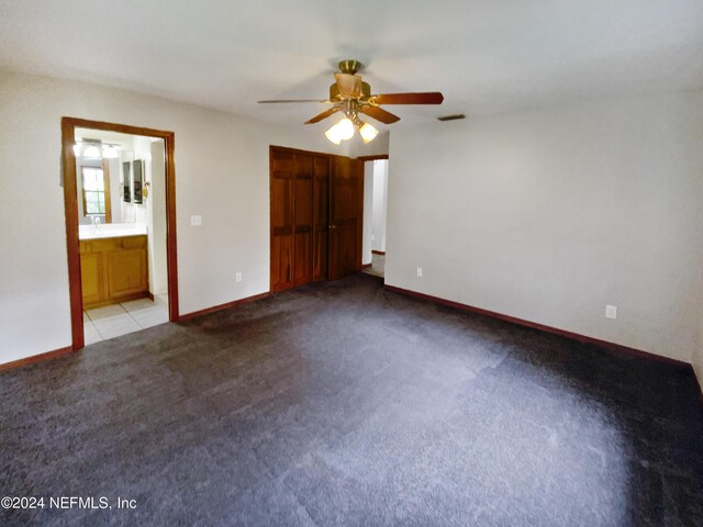 unfurnished bedroom with ensuite bathroom, ceiling fan, and light tile patterned floors