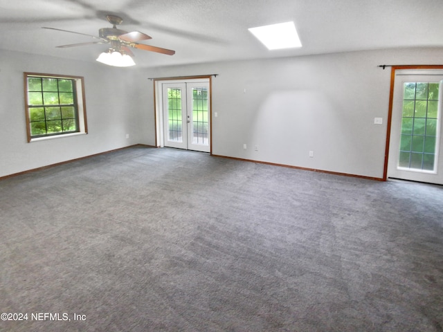 carpeted spare room featuring french doors, ceiling fan, a healthy amount of sunlight, and a textured ceiling