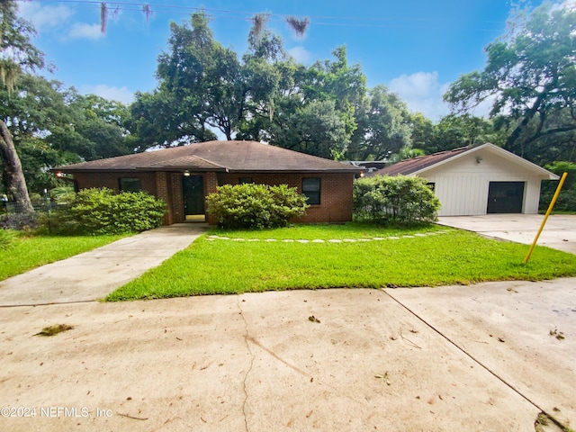 single story home with a front lawn, a garage, and an outbuilding