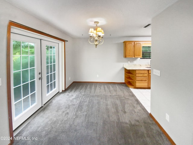 unfurnished dining area featuring light carpet, french doors, and a chandelier