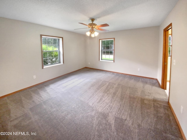 empty room with carpet floors, ceiling fan, a textured ceiling, and a wealth of natural light