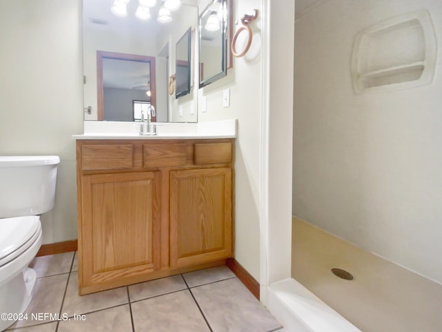 bathroom with tile patterned flooring, vanity, toilet, and walk in shower