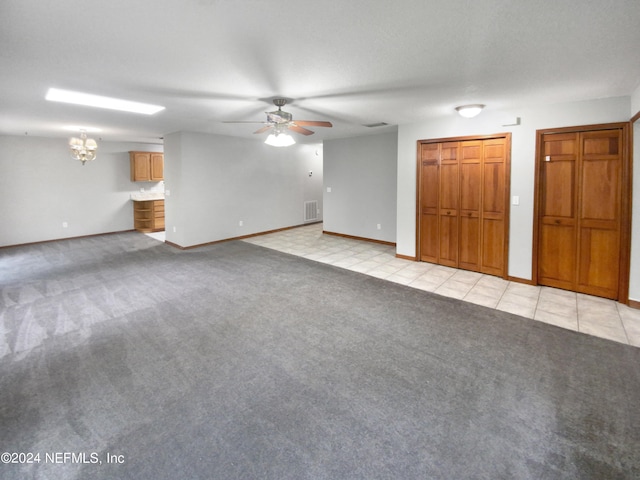 unfurnished living room with ceiling fan with notable chandelier and light colored carpet