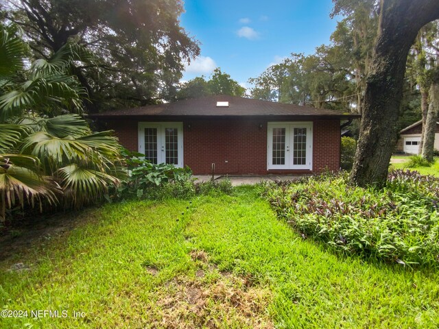 back of house featuring french doors and a lawn