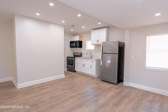 kitchen featuring sink, light wood-type flooring, light stone countertops, stainless steel appliances, and white cabinets