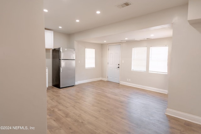 kitchen with freestanding refrigerator, white cabinets, visible vents, and light wood finished floors