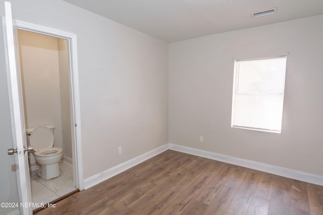 spare room with visible vents, baseboards, and wood finished floors