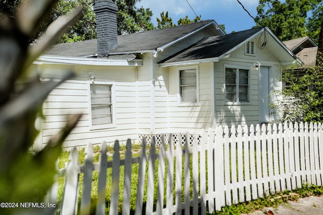 view of side of property featuring a chimney and fence