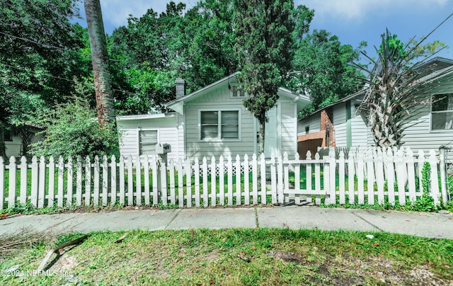 view of front facade featuring a fenced front yard and a chimney