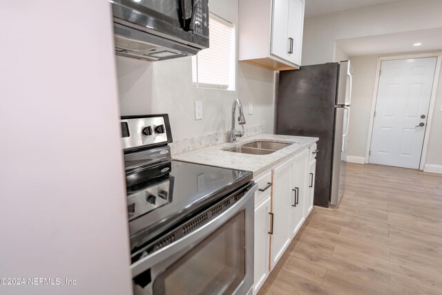 kitchen with sink, stainless steel appliances, white cabinets, and light wood-type flooring