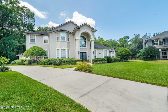 view of front of home featuring driveway, stucco siding, and a front yard