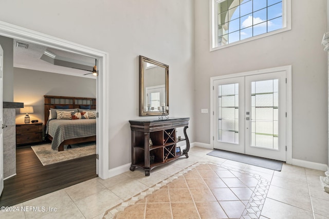 tiled entrance foyer featuring french doors, a towering ceiling, visible vents, and baseboards