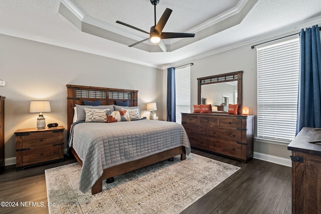 bedroom with a textured ceiling, ornamental molding, a raised ceiling, and dark wood finished floors