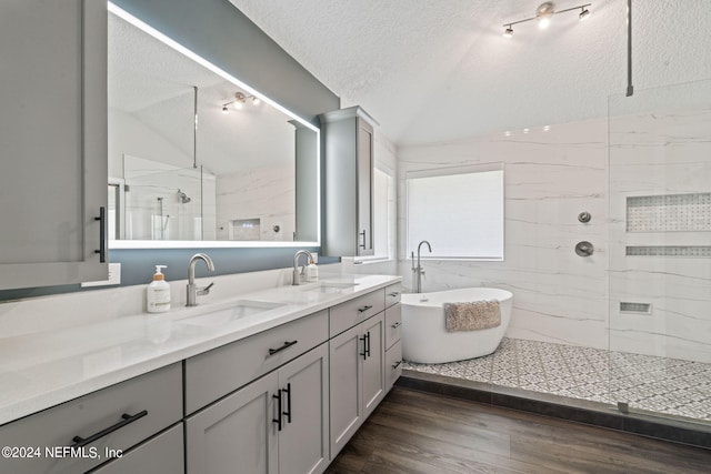 bathroom featuring a sink, a shower stall, vaulted ceiling, and a textured ceiling