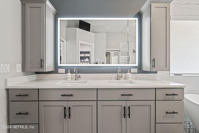 bathroom featuring double vanity, a freestanding tub, a shower stall, and a sink