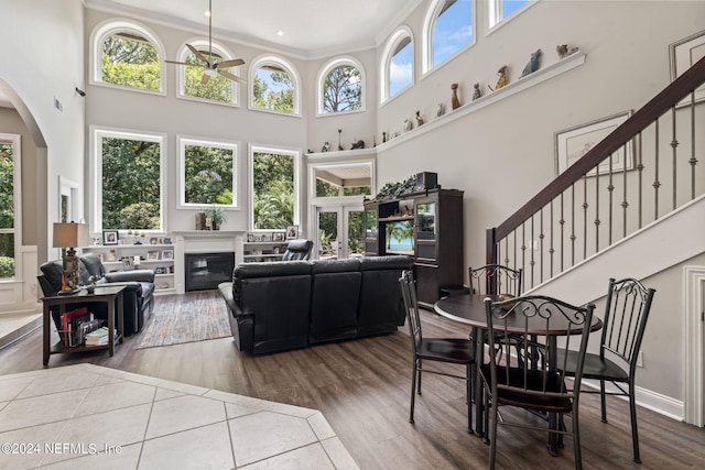 living room with arched walkways, a glass covered fireplace, ceiling fan, stairway, and wood finished floors