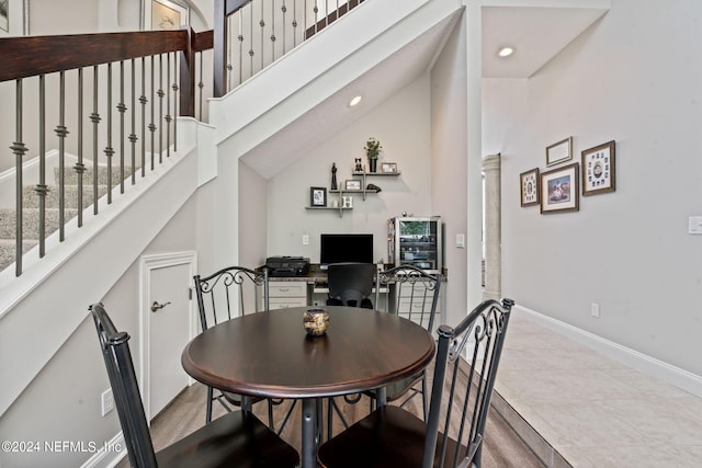 dining space with stairs, recessed lighting, a towering ceiling, and baseboards